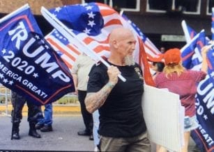 Rally organizer Chester Doles carries Trump 2020 banner.